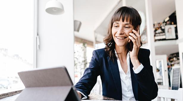 An investment advisor happily talks on the phone with a client while using Schwab tools.